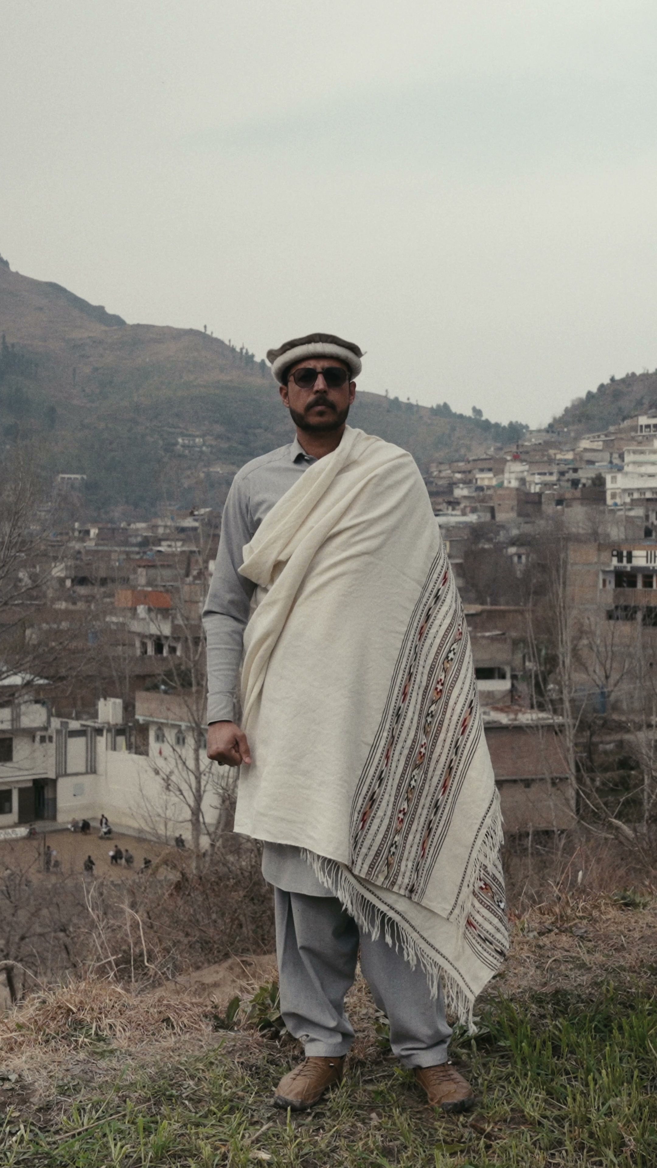 A man draping a cream wool shawl around his shoulders