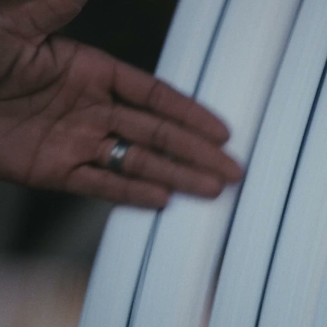 An open hand with a ring resting against a fold of pale white wool cloth