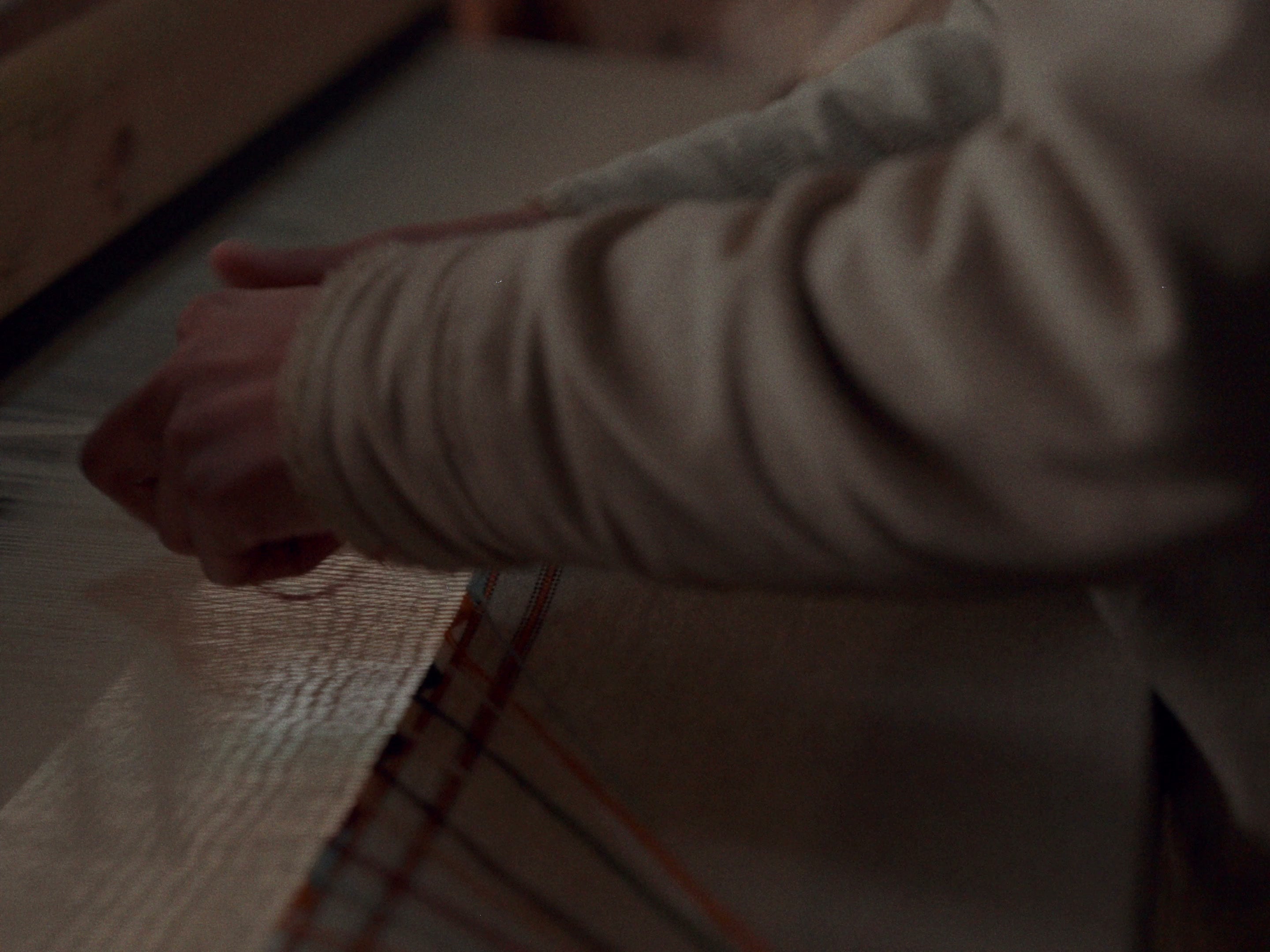 A man in cream clothing working at the loom, seen from the side
