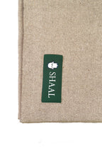 Close-up of a Beige shawl with a green label featuring the 'SHAAL' brand on a white background.