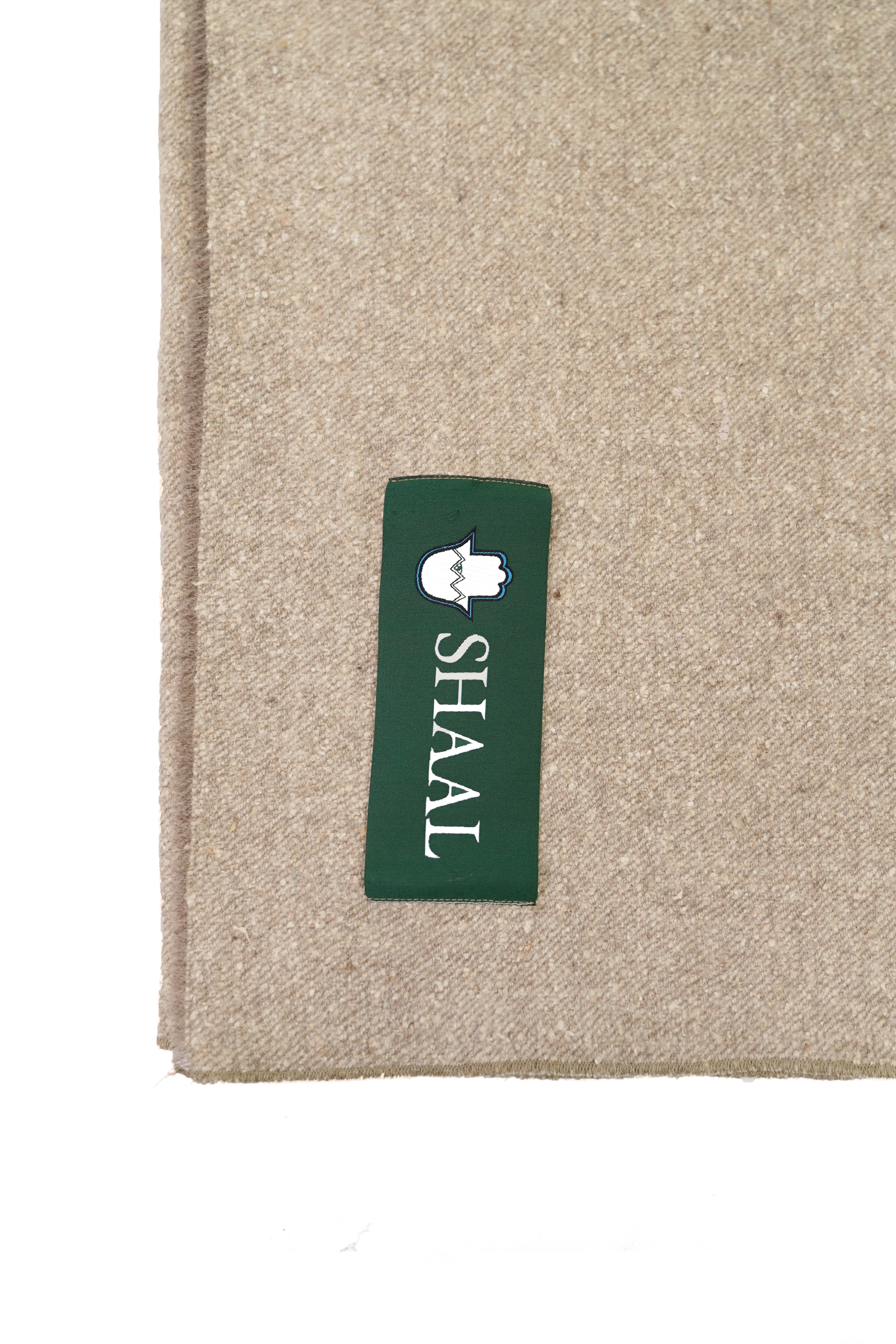 Close-up of a Beige shawl with a green label featuring the 'SHAAL' brand on a white background.