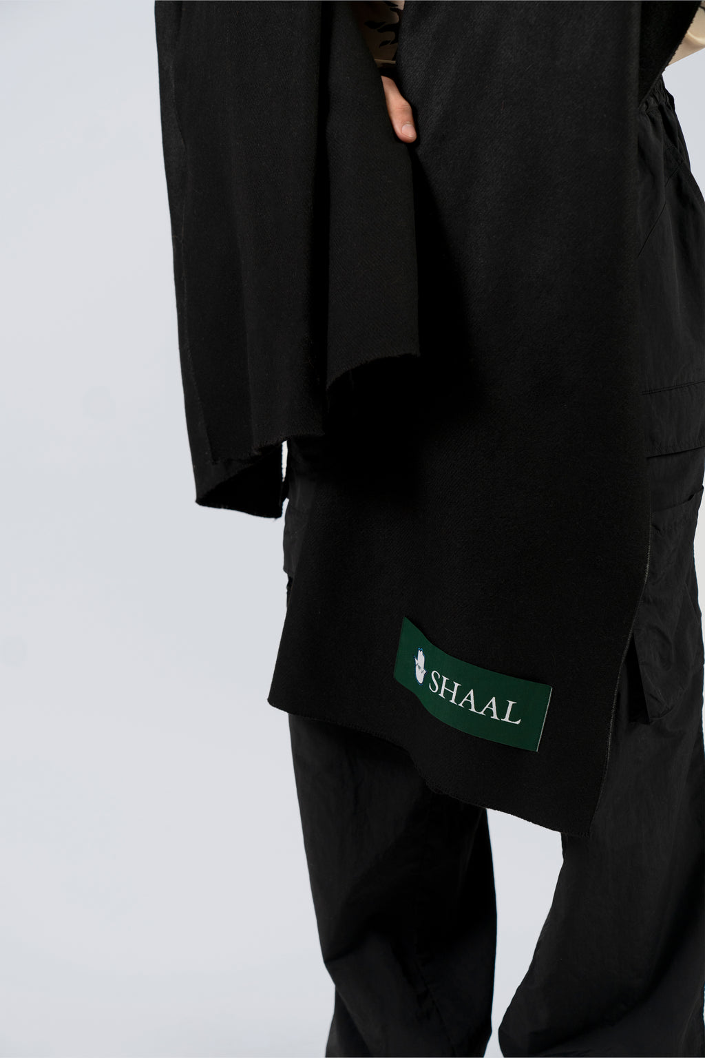 Black pashmina shawl mid-body close-up with SHAAL label drape detail