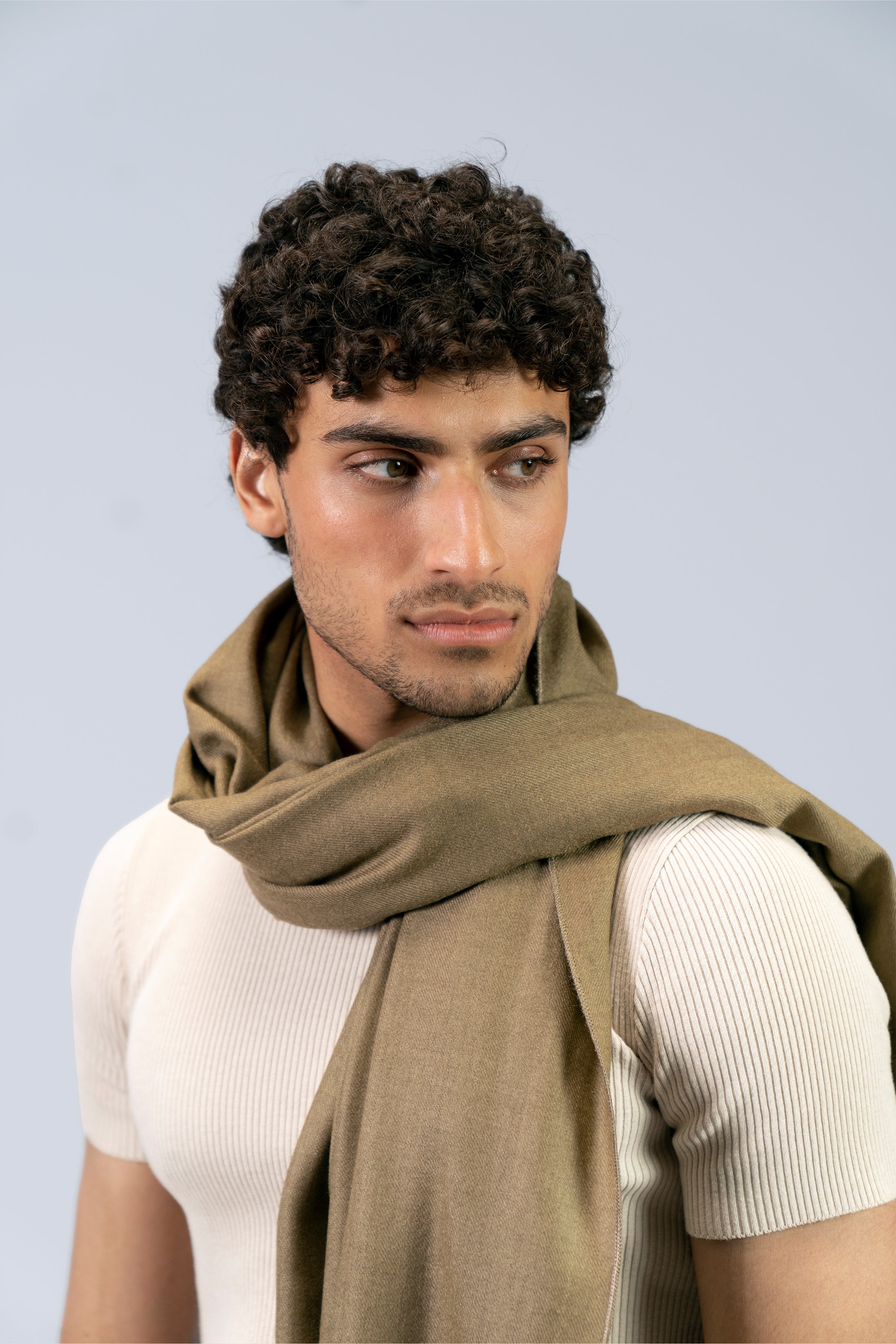 Gold pashmina shawl close-up wrapped at neck on male model, three-quarter portrait