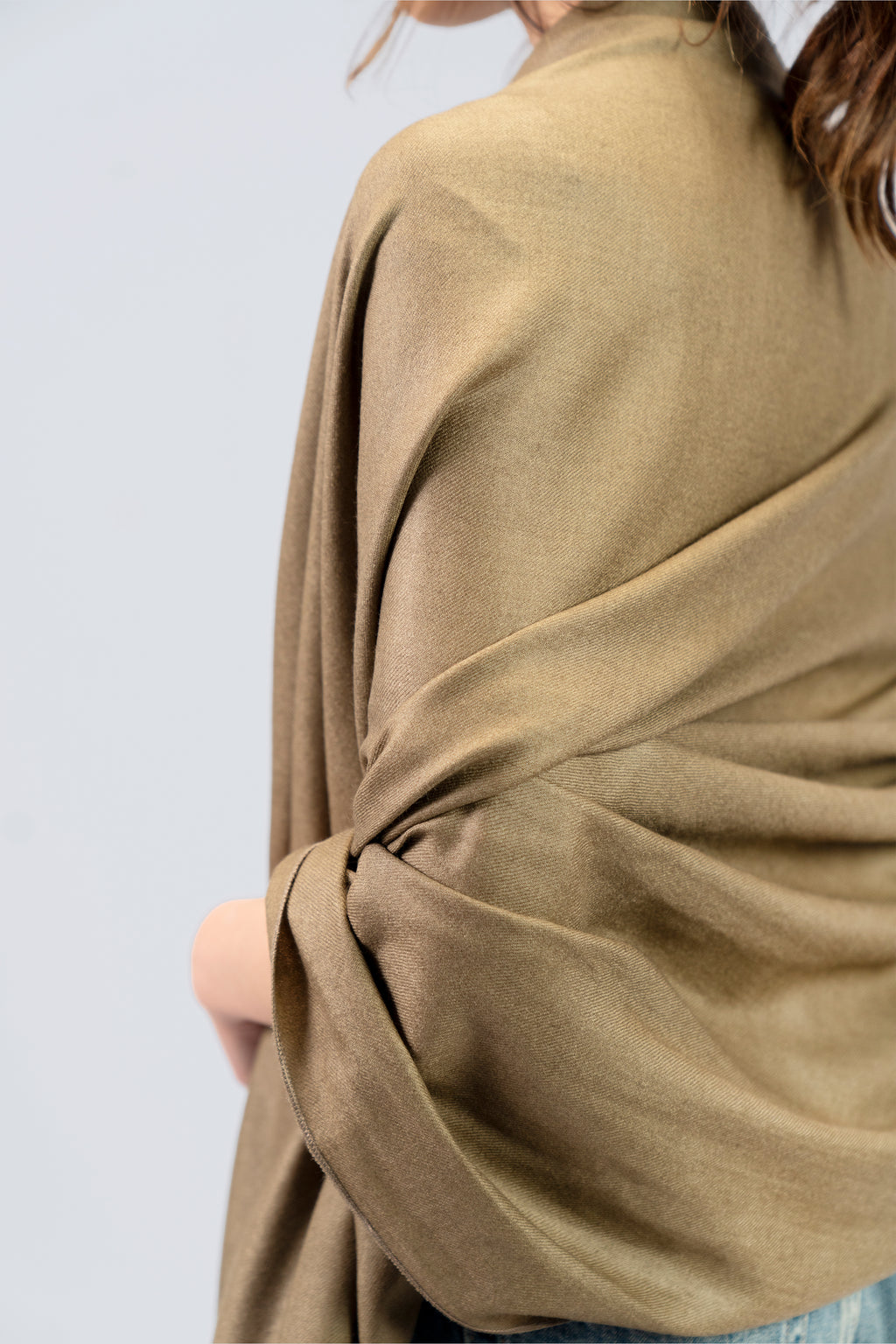 Gold pashmina shawl close-up of soft drape and twist on female model's back