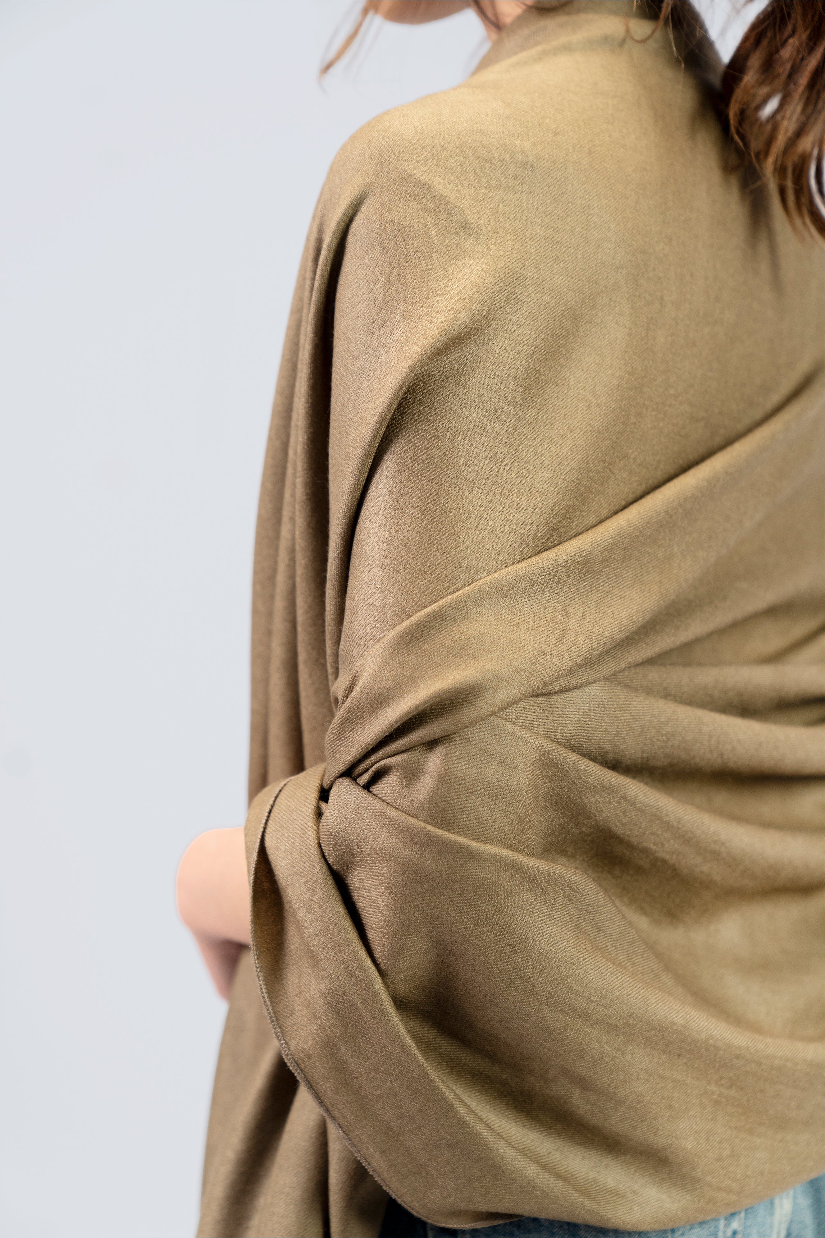 Gold pashmina shawl close-up of soft drape and twist on female model's back